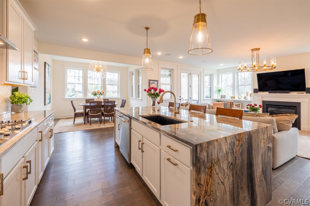 Kitchen featuring light stone counters, plenty of natural light, pendant lighting, and dark hardwood / wood-style floors