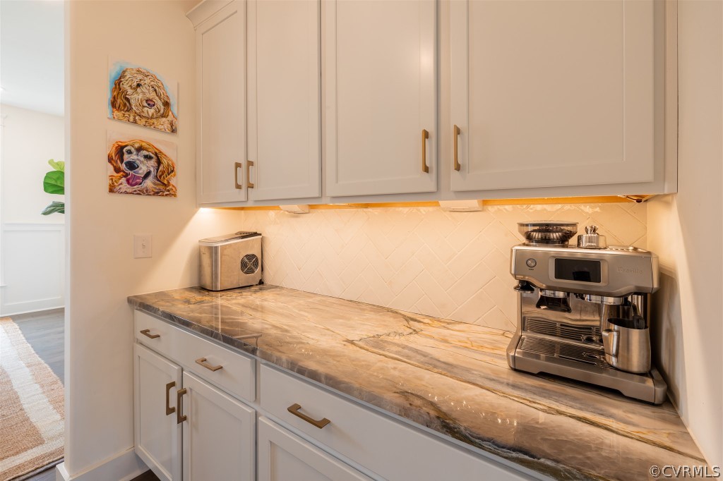 Kitchen with backsplash, hardwood / wood-style flooring, gray cabinetry, and light stone countertops
