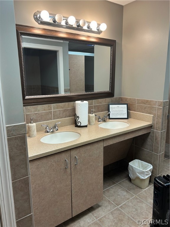 Women's Bathroom featuring backsplash, dual bowl vanity, tile flooring, and tile walls