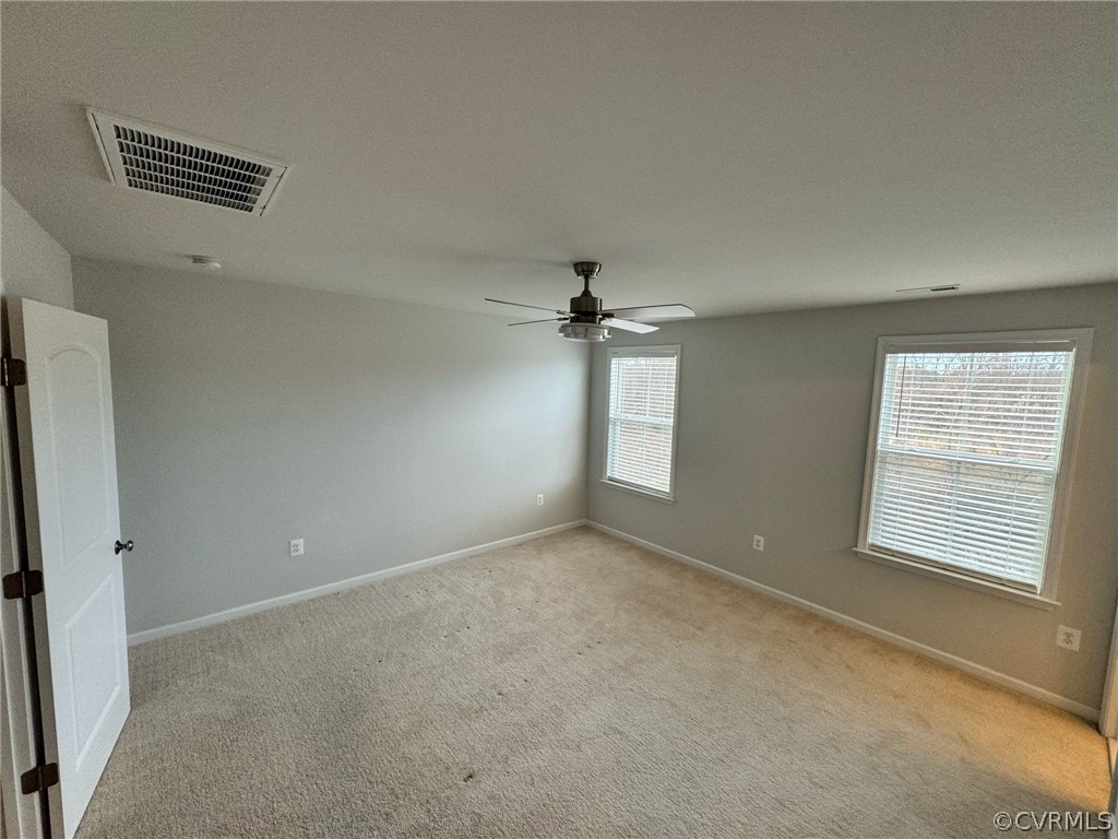 Empty room with a wealth of natural light, carpet, and ceiling fan