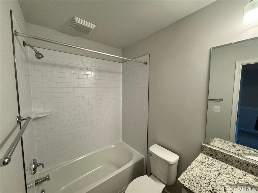Full bathroom with tiled shower / bath, vanity, and toilet