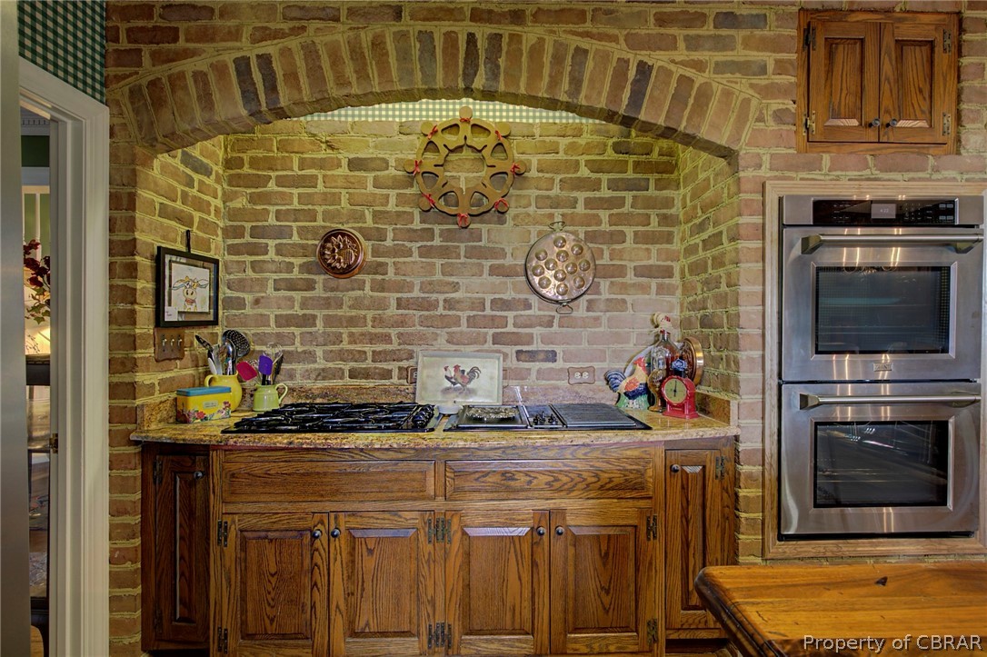 Kitchen featuring stainless steel double oven and brick wall