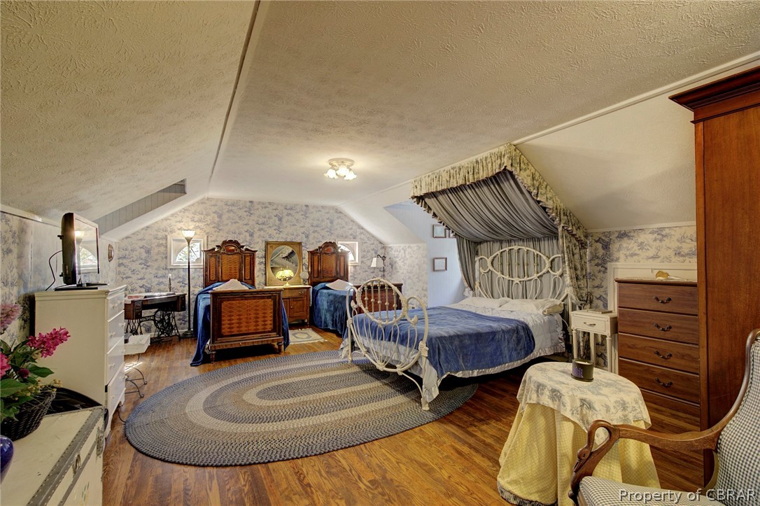 Bedroom featuring a textured ceiling, hardwood / wood-style floors, and vaulted ceiling