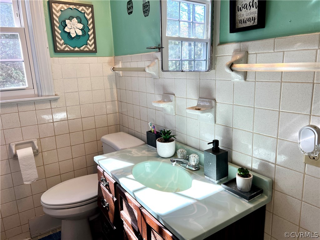 Bathroom featuring tile walls, vanity, and toilet