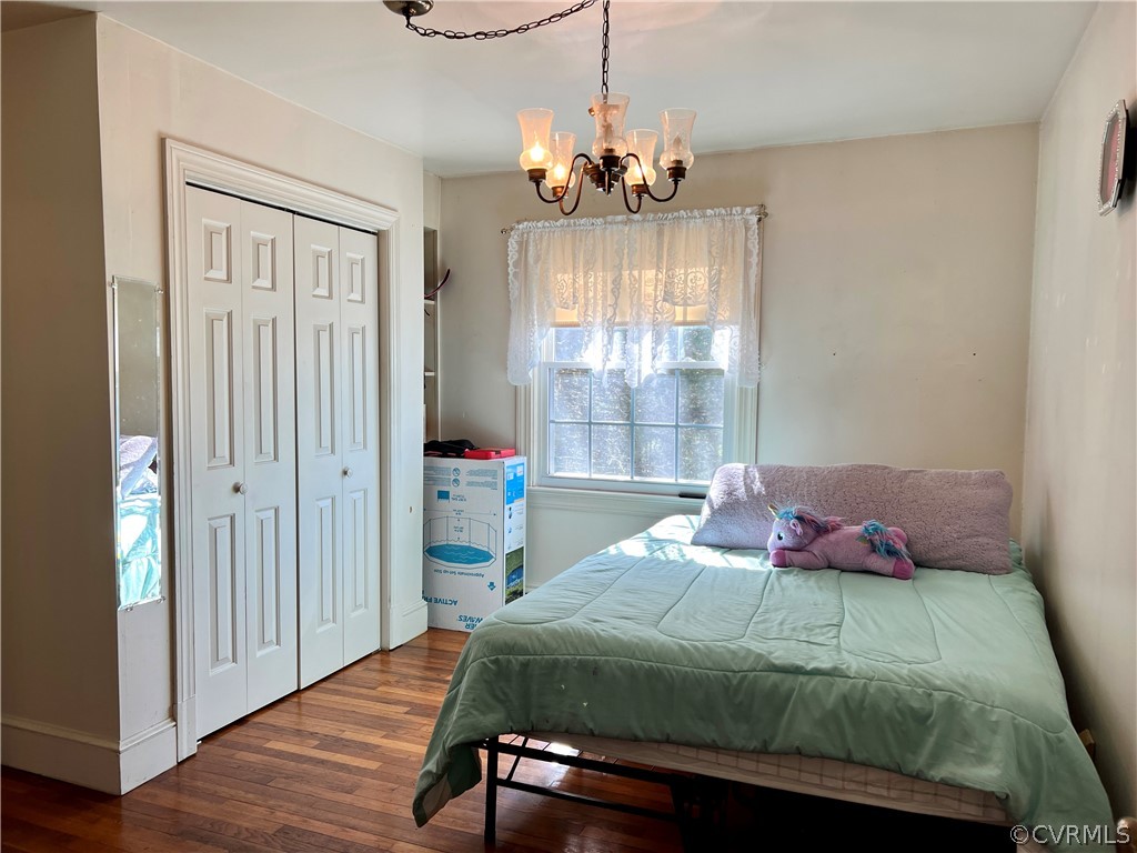 Bedroom with a notable chandelier, hardwood / wood-style flooring, and a closet