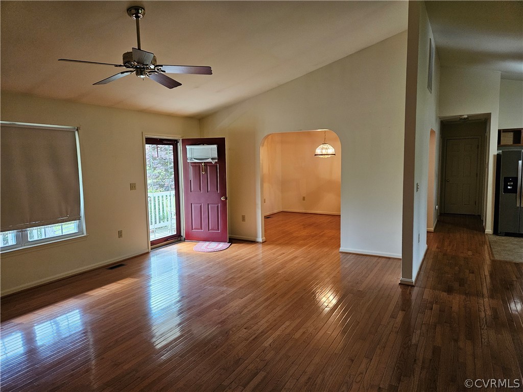 Unfurnished room with high vaulted ceiling, dark wood-type flooring, and ceiling fan