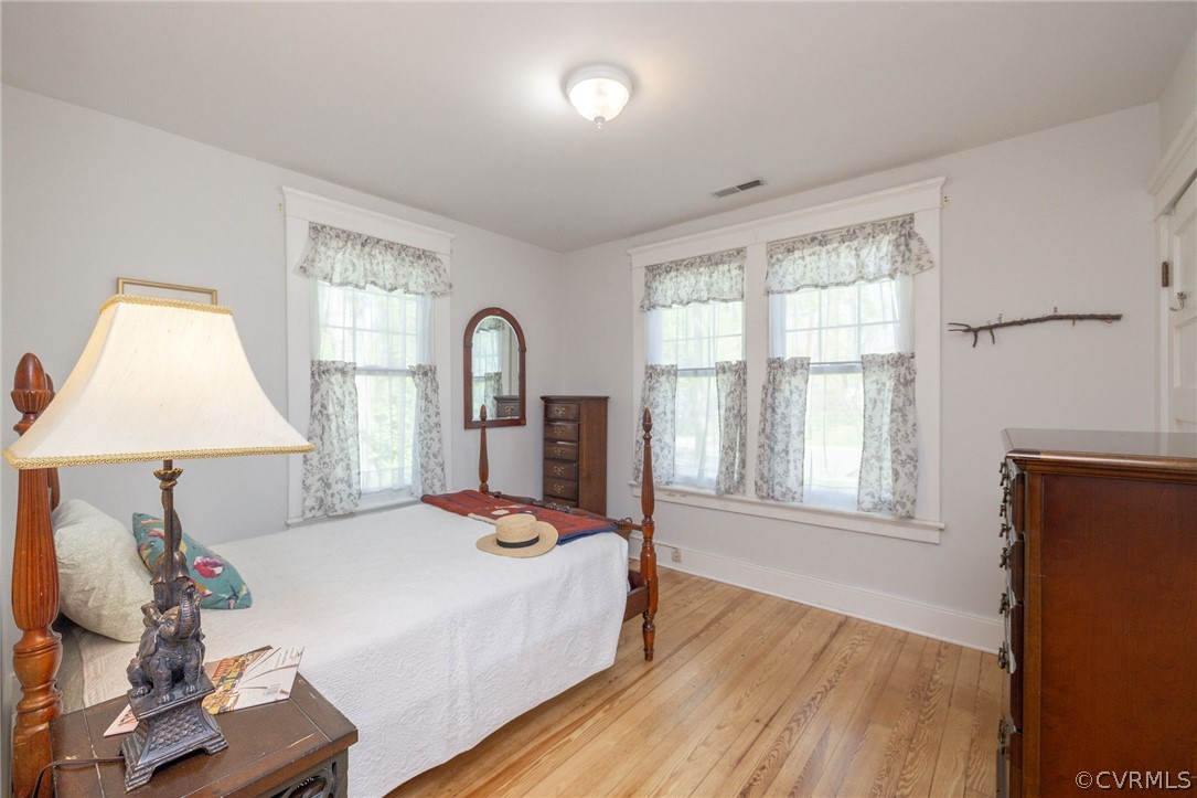 Bedroom with light hardwood / wood-style floors and multiple windows