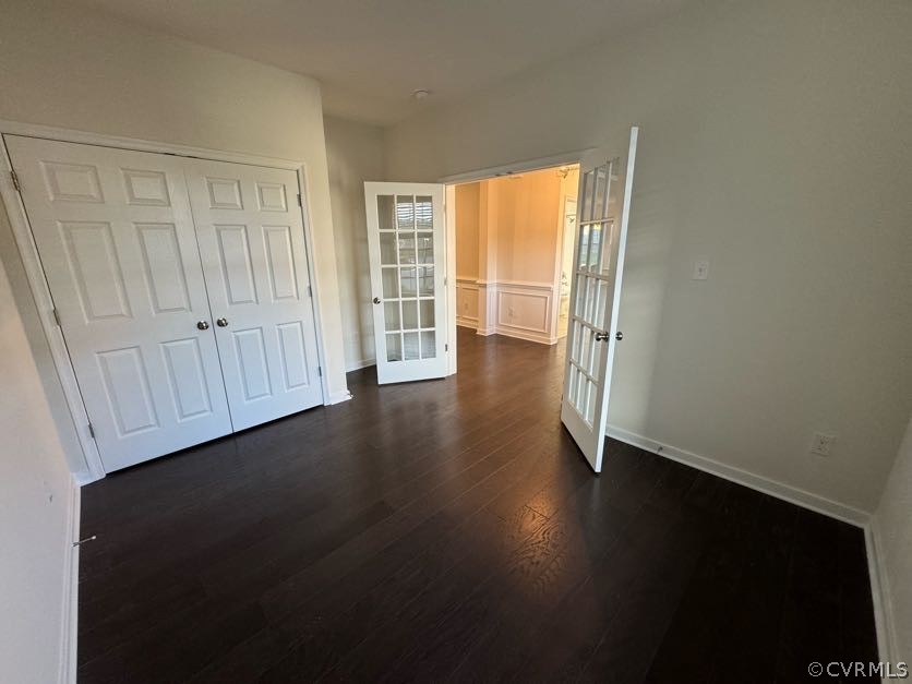 Unfurnished bedroom with dark hardwood / wood-style flooring, french doors, and a closet