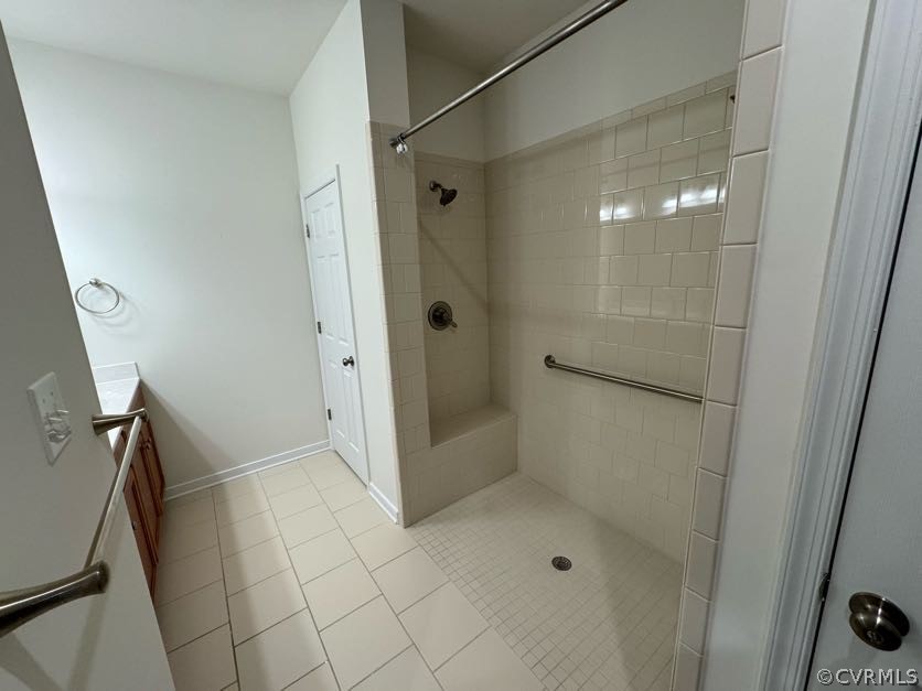 Bathroom with tile flooring, tiled shower, and vanity