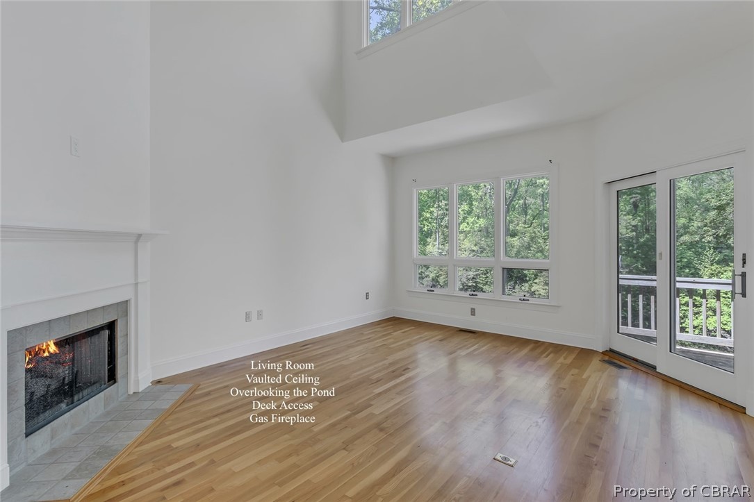 Unfurnished living room with plenty of natural light, a high ceiling, light hardwood / wood-style flooring, and a fireplace