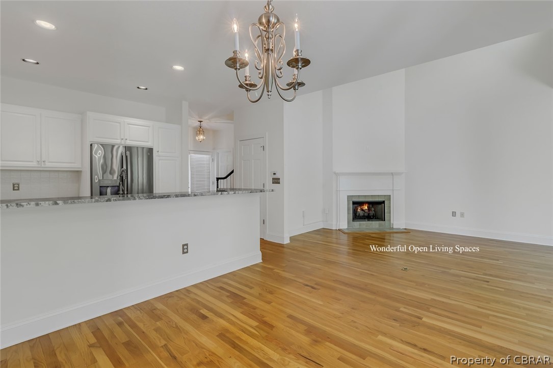 Unfurnished living room with light hardwood / wood-style floors and a notable chandelier