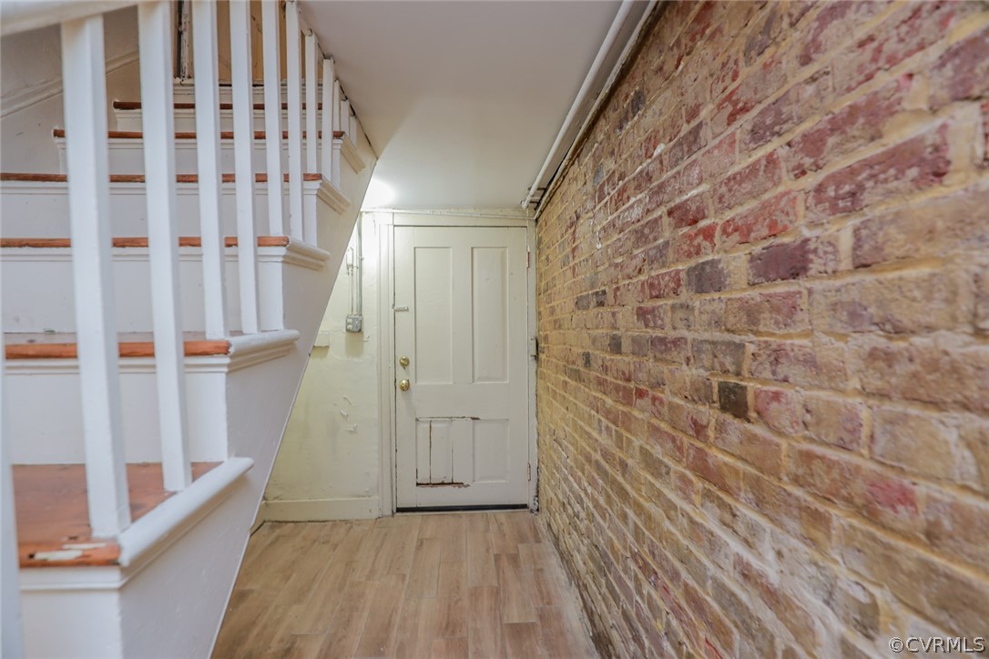 Hallway featuring brick wall and hardwood / wood-style flooring