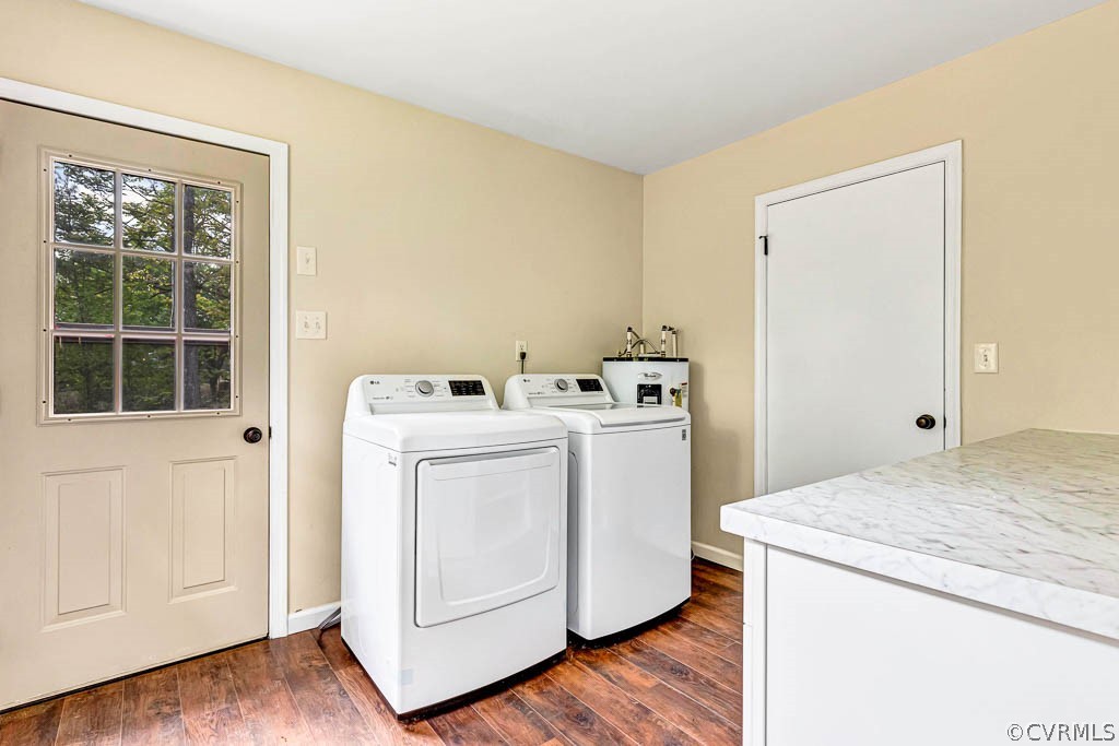Washroom with dark hardwood / wood-style flooring, water heater, and washing machine and clothes dryer