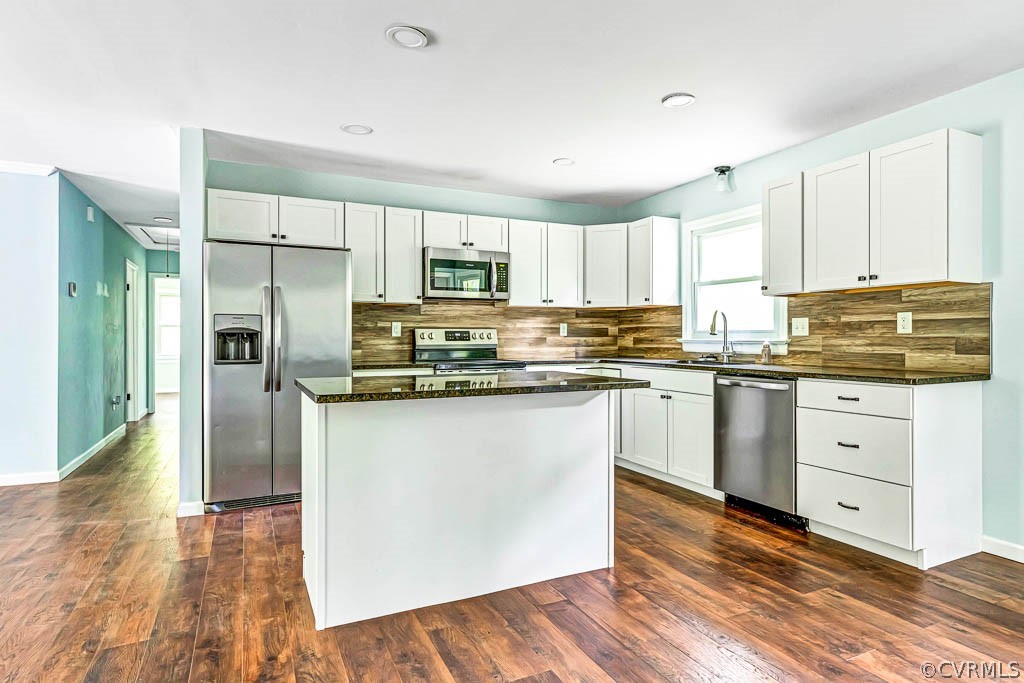 Kitchen featuring a center island, tasteful backsplash, appliances with stainless steel finishes, and dark hardwood / wood-style floors