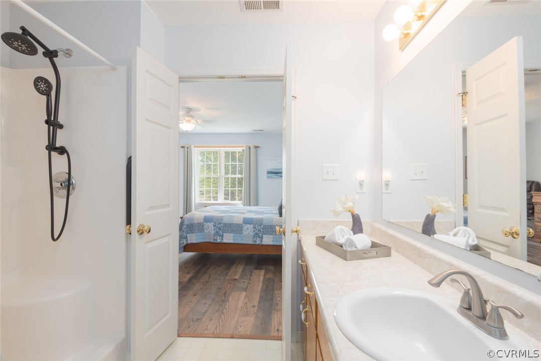 Bathroom featuring hardwood / wood-style floors, ceiling fan, and large vanity