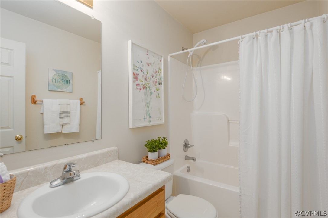 Full bathroom featuring shower / tub combo with curtain, vanity, and toilet