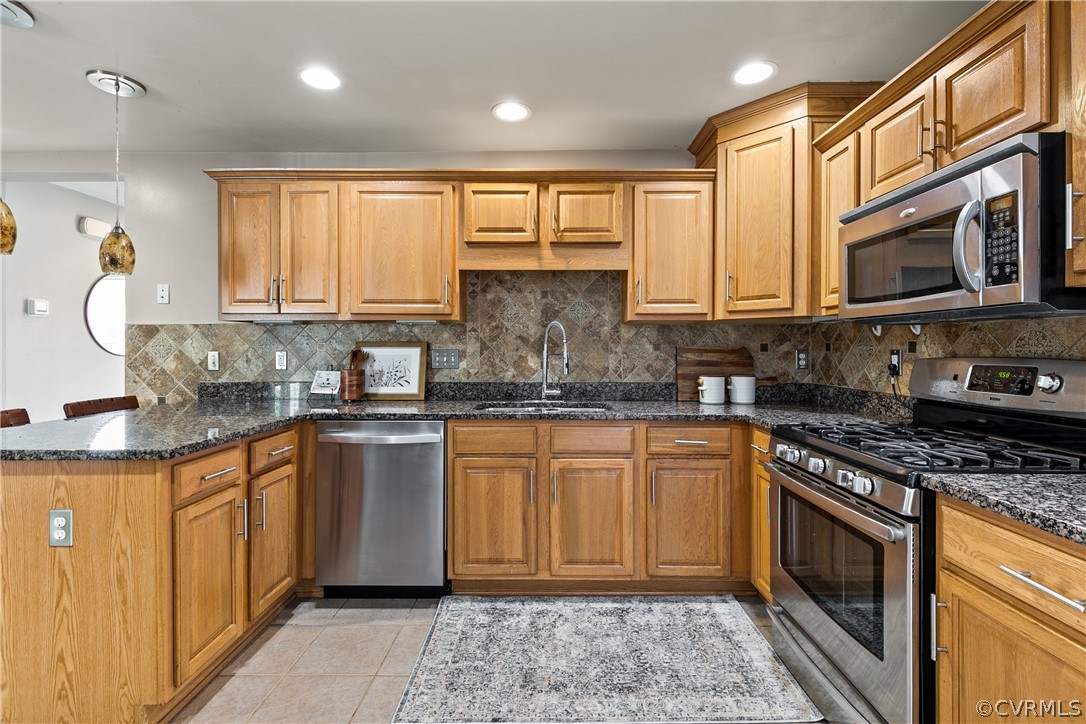 Kitchen featuring sink, stainless steel appliances, light tile floors, and tasteful backsplash