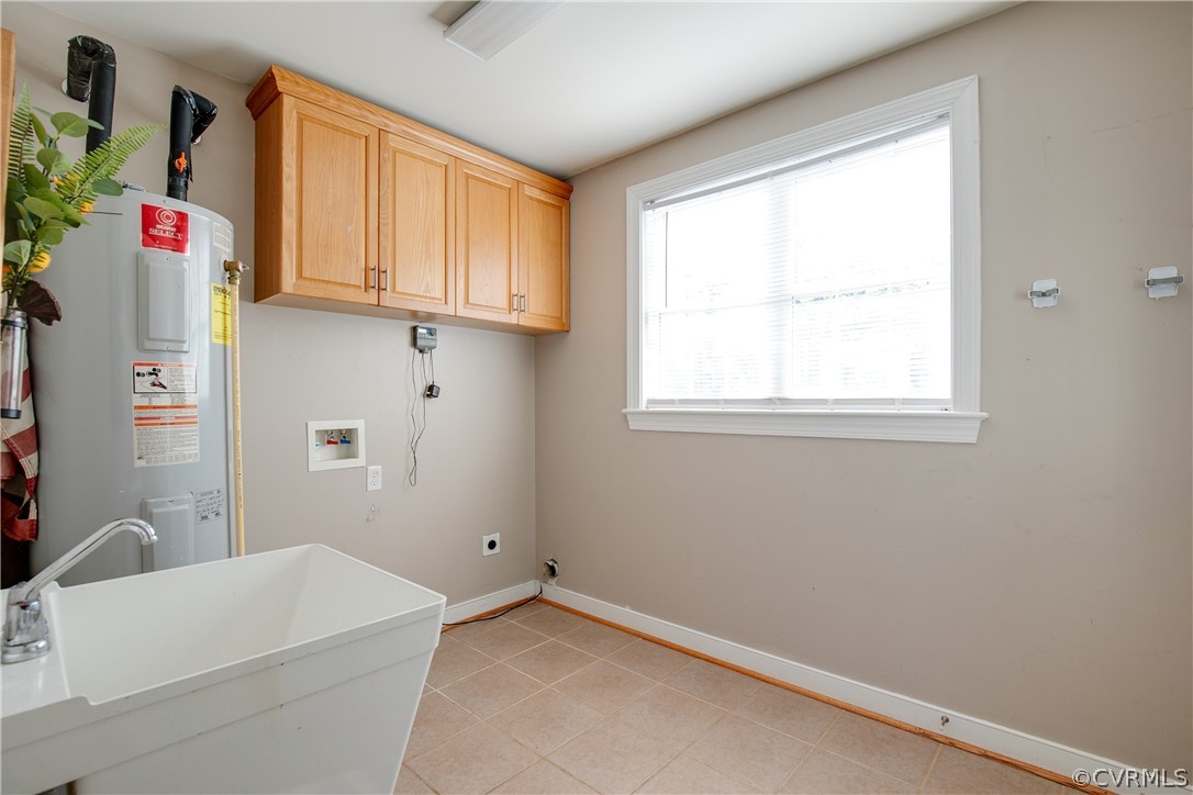 Laundry area featuring cabinets, sink, light tile flooring, water heater, and hookup for an electric dryer
