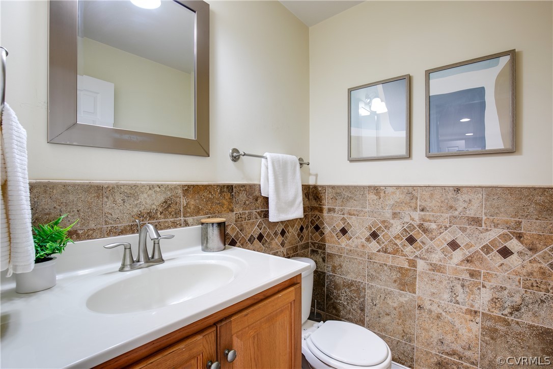 Bathroom featuring backsplash, tile walls, toilet, and large vanity
