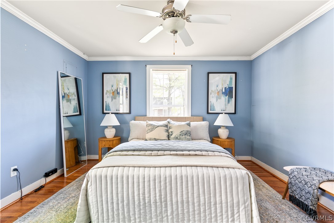 Bedroom featuring ceiling fan, dark wood-type flooring, and ornamental molding