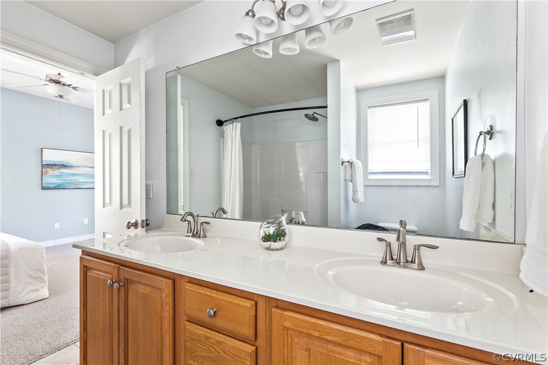 Bathroom with oversized vanity, ceiling fan, and double sink