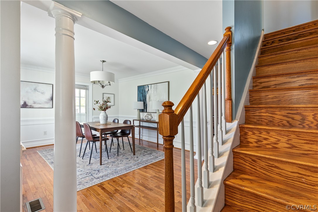 Stairway featuring hardwood / wood-style floors, ornamental molding, and ornate columns