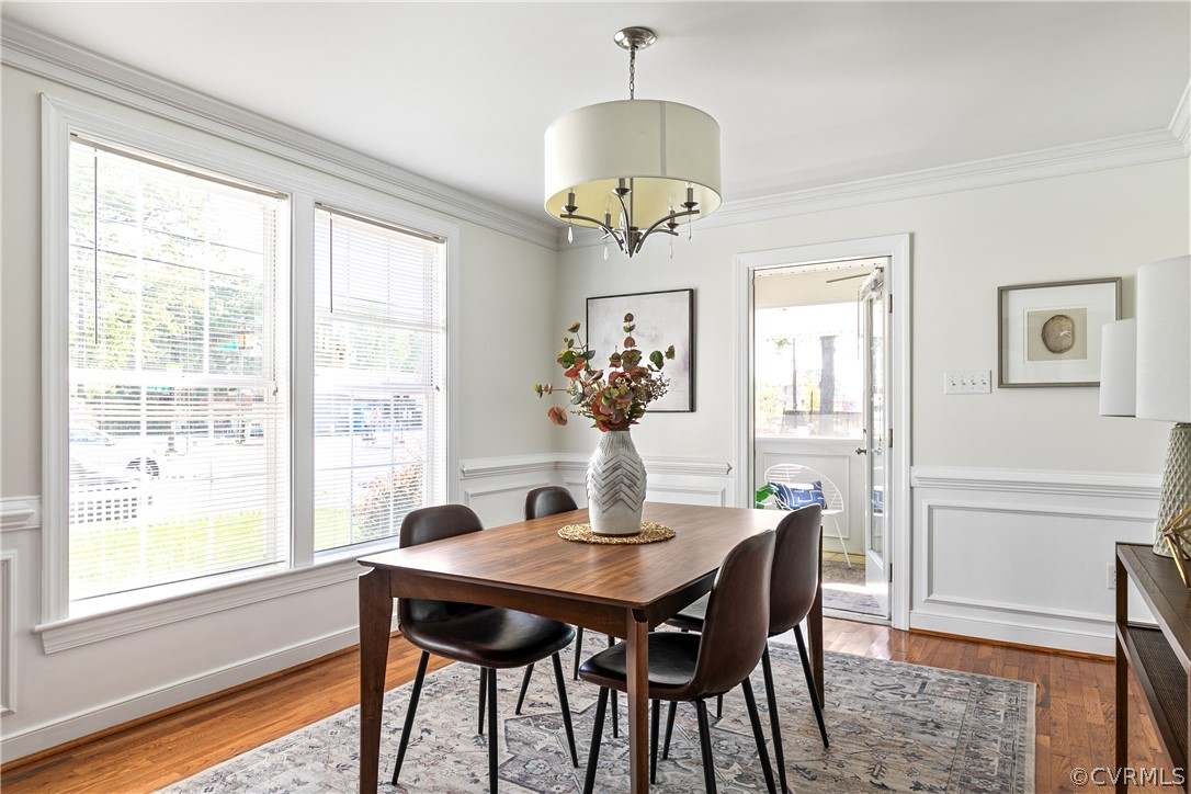 Dining space with a wealth of natural light, crown molding, and dark hardwood / wood-style flooring