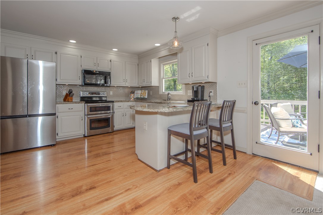 Kitchen featuring white cabinets, granite counter tops, tasteful backsplash, stainless steel appliances opens to rear deck!
