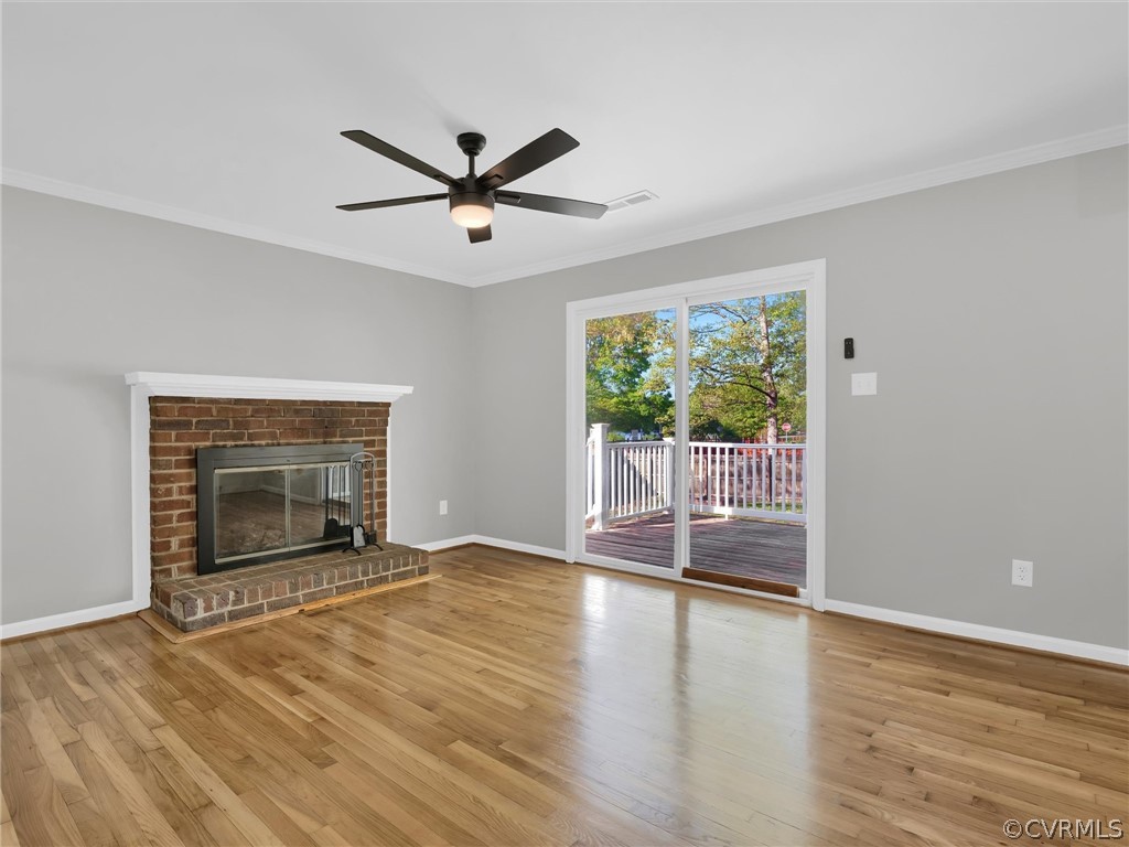 Unfurnished living room with ornamental molding, light hardwood / wood-style flooring, ceiling fan, and a fireplace