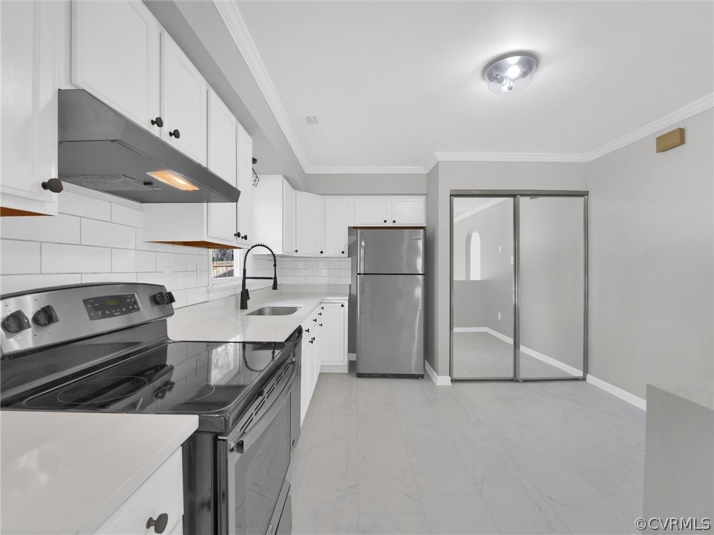 Kitchen featuring backsplash, appliances with stainless steel finishes, white cabinets, and light tile flooring