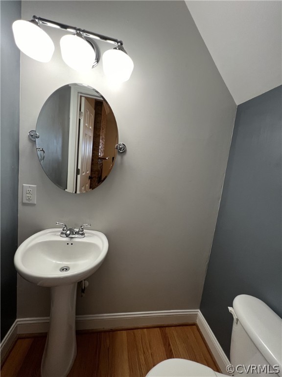 Bathroom with vaulted ceiling, hardwood / wood-style flooring, and toilet