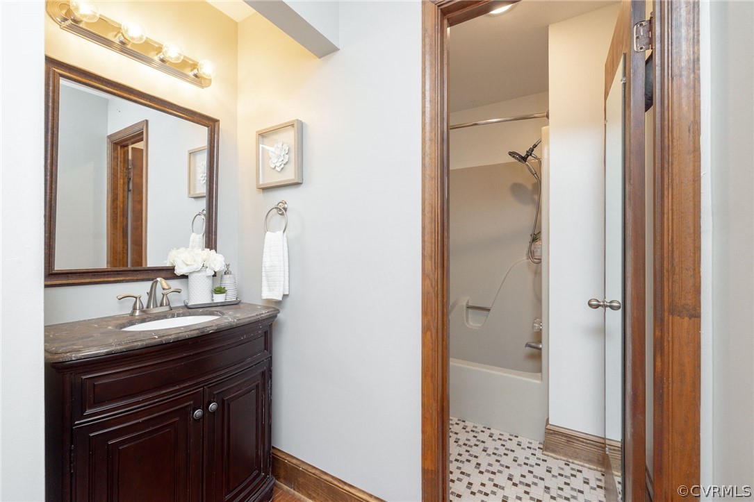 Bathroom with tile flooring, oversized vanity, and shower / washtub combination