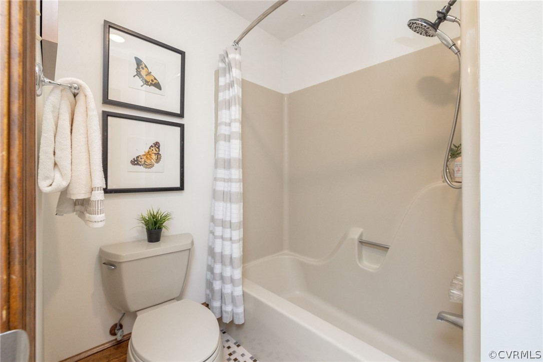 Bathroom with toilet, tile flooring, and shower / bath combo with shower curtain