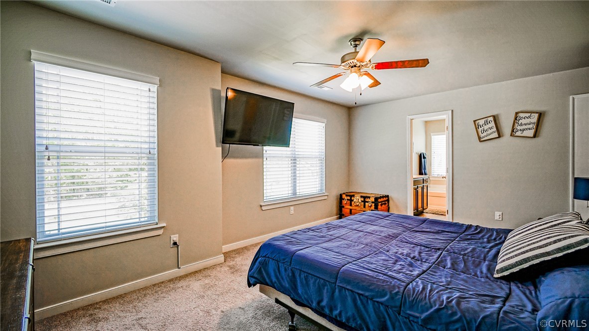 Bedroom featuring carpet flooring, ensuite bath, and ceiling fan