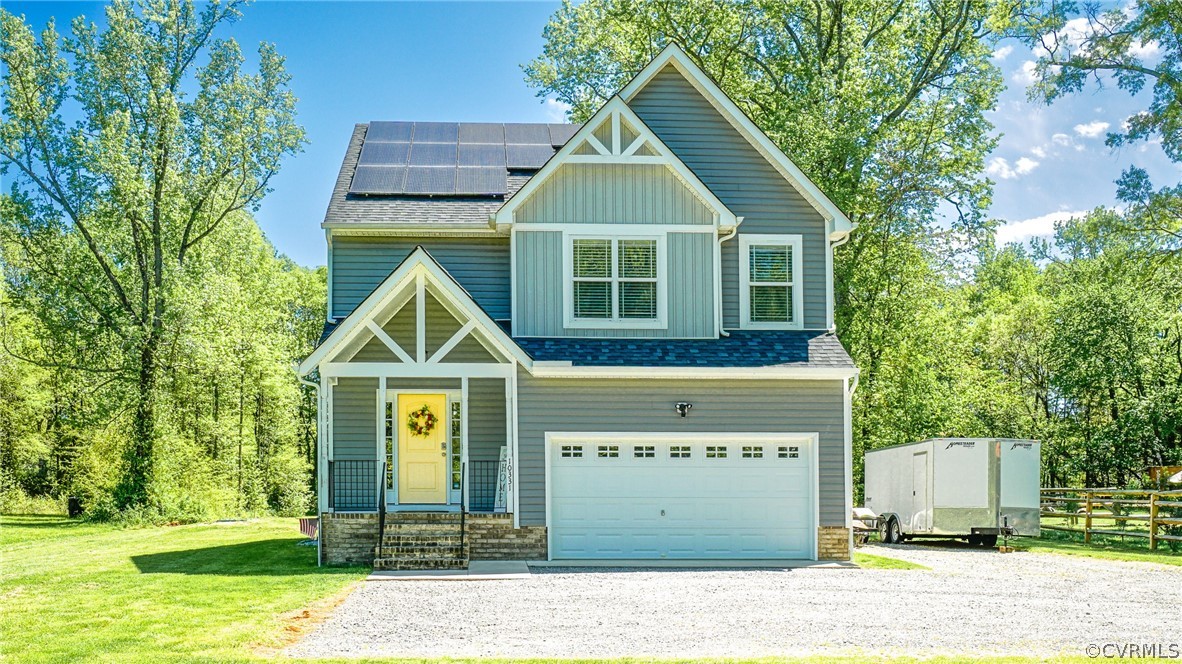 Craftsman inspired home featuring solar panels, a garage, and a front lawn