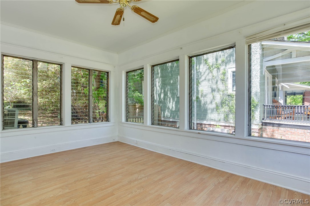 Unfurnished sunroom with a wealth of natural light and ceiling fan