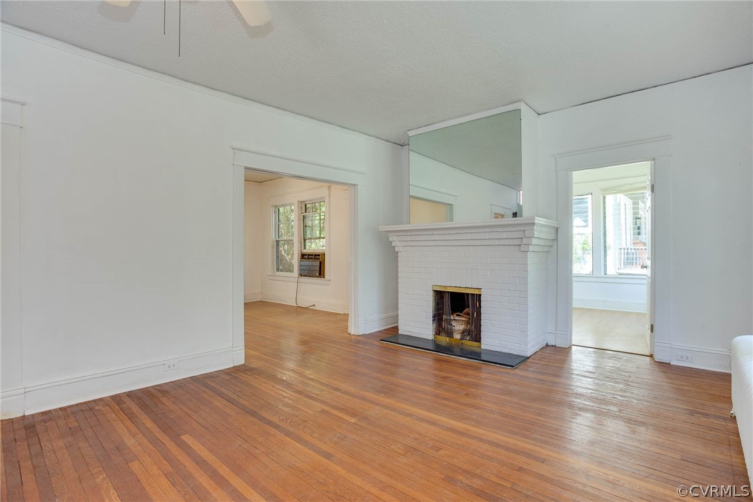 Unfurnished living room featuring plenty of natural light, a fireplace, ceiling fan, and hardwood / wood-style flooring