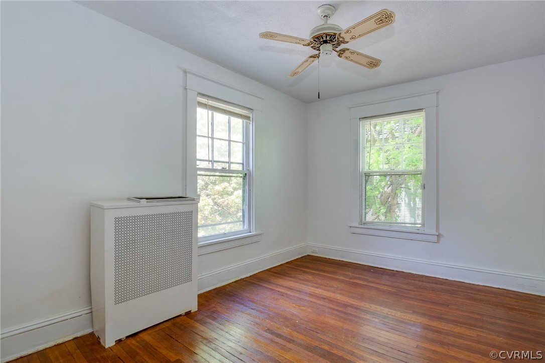 Spare room featuring dark hardwood / wood-style flooring, ceiling fan, and a wealth of natural light