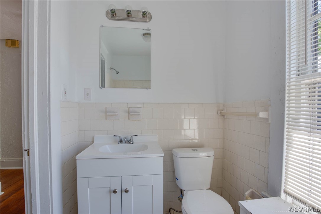Bathroom with tile walls, large vanity, wood-type flooring, and toilet