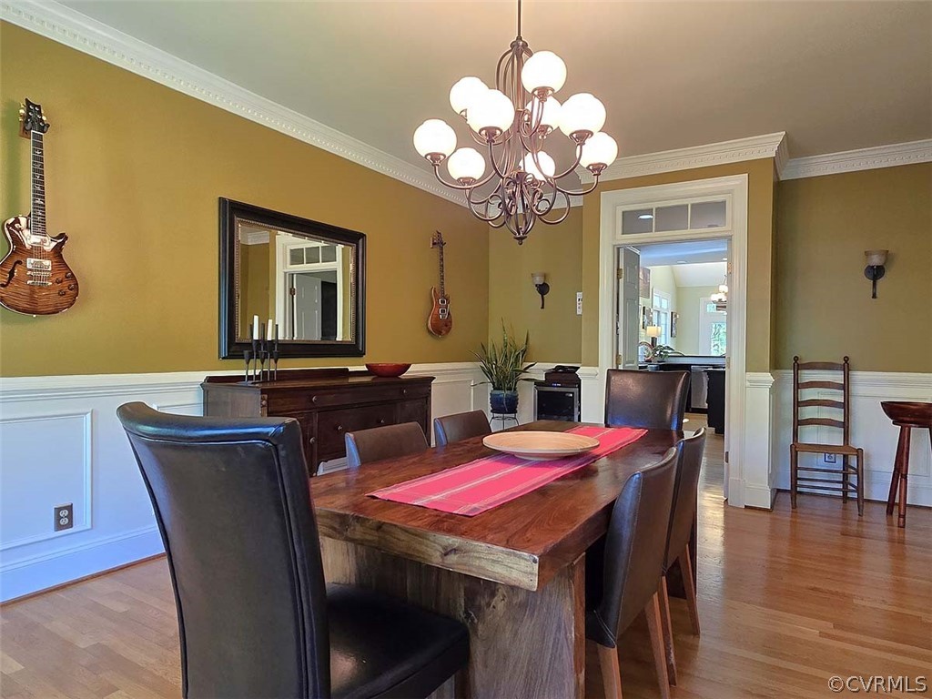 Dining space with a notable chandelier, light hardwood / wood-style floors, and crown molding