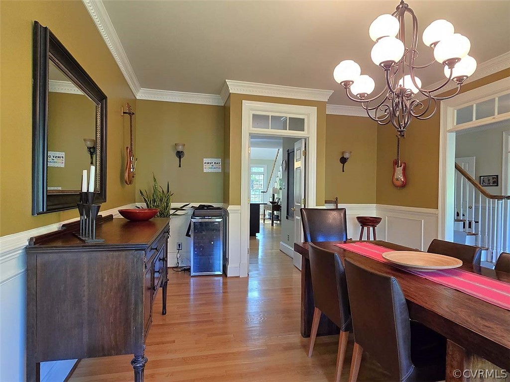 Dining area with ornamental molding, an inviting chandelier, and light hardwood / wood-style flooring