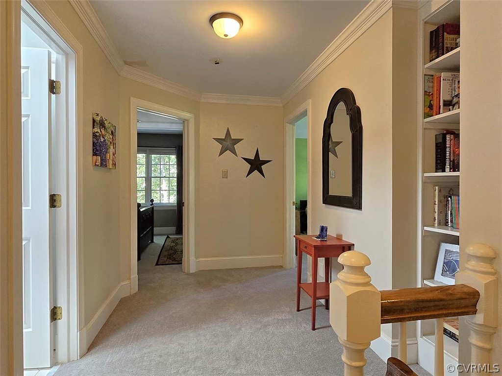 Corridor featuring ornamental molding, light colored carpet, and built in shelves