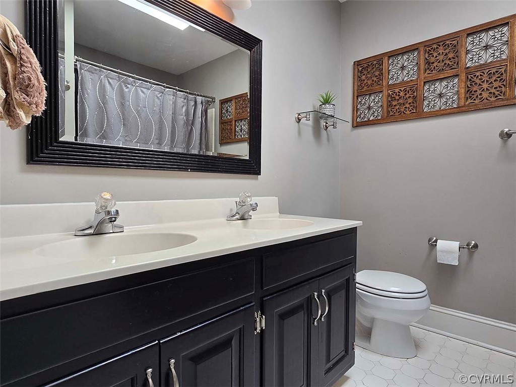 Bathroom with tile floors, toilet, and dual bowl vanity