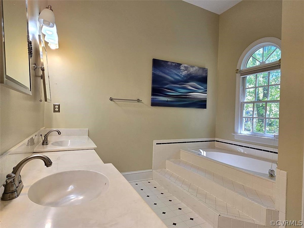 Bathroom featuring a relaxing tiled bath, tile floors, and double sink vanity