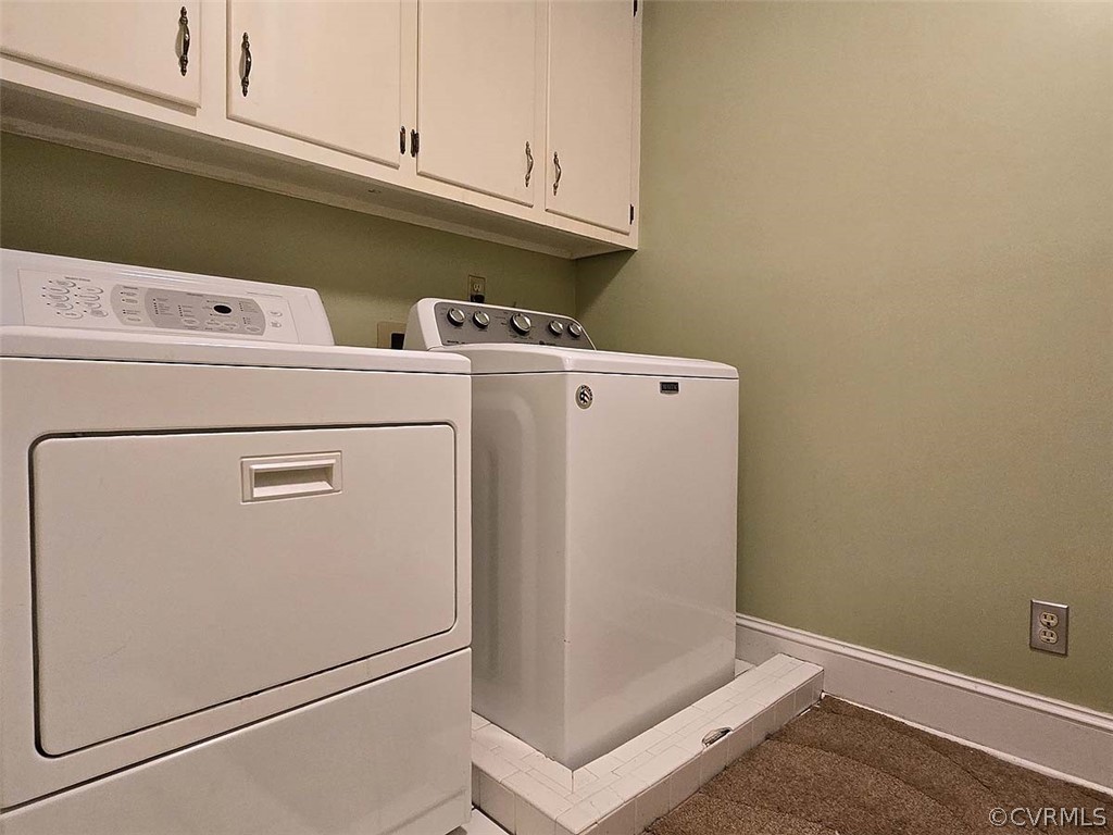 Laundry room with light colored carpet, cabinets, and separate washer and dryer