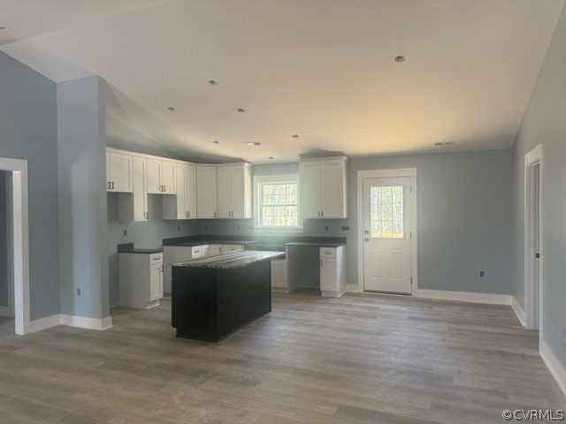 Kitchen with a kitchen island, high vaulted ceiling, white cabinets, and hardwood / wood-style flooring