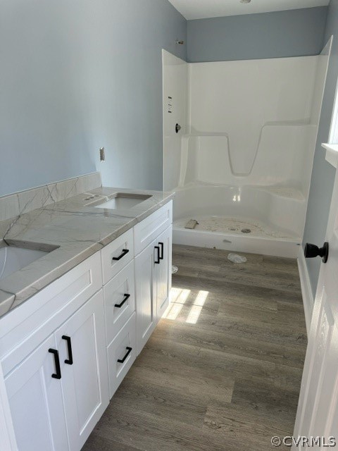 Bathroom featuring double vanity, hardwood / wood-style flooring, and walk in shower