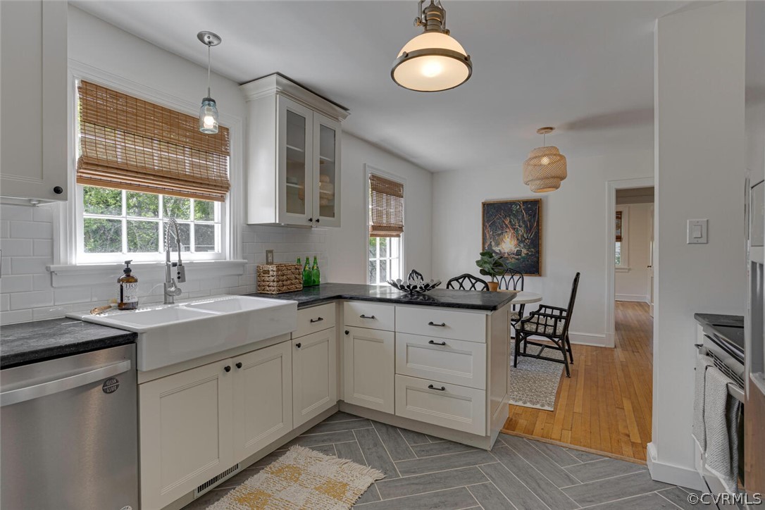 Kitchen featuring pendant lighting, sink, tasteful backsplash, light hardwood / wood-style floors, and dishwasher