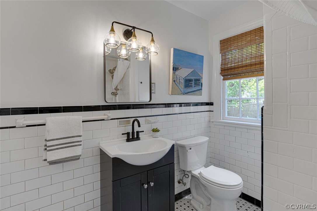 Bathroom featuring oversized vanity, tile walls, toilet, and tile floors