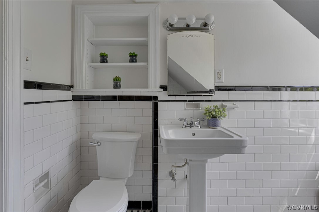 Bathroom featuring backsplash, toilet, and tile walls